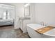 Modern bathroom features a soaking tub with a wooden tray, tile floors, and a bedroom view at 6838 Prelude Dr, Atlanta, GA 30328