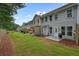 Backyard view featuring green grass, a patio, and a row of townhomes with neutral colored exteriors at 411 Mountain View Ln, Woodstock, GA 30188