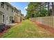 View of backyard featuring green grass, a patio, and a row of townhomes with neutral colored exteriors, and a wooden fence at 411 Mountain View Ln, Woodstock, GA 30188