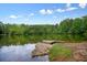 Scenic lake view featuring lush green trees and a clear blue sky with scattered clouds at 411 Mountain View Ln, Woodstock, GA 30188