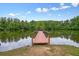 Picturesque wooden dock extends into a serene pond, framed by lush trees and a clear sky at 411 Mountain View Ln, Woodstock, GA 30188