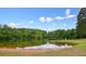 Tranquil pond reflecting the sky, featuring a wooden dock and surrounded by lush green landscape at 411 Mountain View Ln, Woodstock, GA 30188