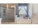 Bathroom showcases a tub with blue curtains and glass enclosed shower at 5915 Partners Pass, Cumming, GA 30028