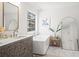 Bright bathroom with a soaking tub, carved vanity, and marble floors at 7880 Brands Hatch Blvd, Cumming, GA 30040