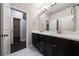 Well-lit bathroom featuring a double vanity with dark cabinets and white countertops, adjacent to an open closet space at 10580 Grandview Sq, Johns Creek, GA 30097