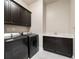 Well-equipped laundry room with modern washer and dryer, sink, and dark cabinets for storage at 10580 Grandview Sq, Johns Creek, GA 30097