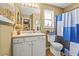 Bathroom featuring a single sink vanity, framed mirror, and a shower-tub combo with blue curtain at 47 Powder Springs St, Hiram, GA 30141