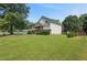 Two-story home with a large yard, mature trees, and neutral siding on a sunny day at 47 Powder Springs St, Hiram, GA 30141