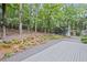 Landscaped backyard featuring a gravel and deck area surrounded by lush trees at 115 Leaf Lake Dr, Suwanee, GA 30024