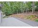 Backyard with a gravel and deck area surrounded by lush greenery and trees at 115 Leaf Lake Dr, Suwanee, GA 30024