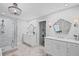 Bright bathroom featuring double vanities, a chandelier, and a glass enclosed shower with herringbone-patterned tile at 115 Leaf Lake Dr, Suwanee, GA 30024
