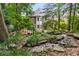 Back exterior of house with a waterfall and creek running through a lush garden at 3699 Canyon Ridge Ne Ct, Brookhaven, GA 30319