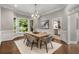 Formal dining room with modern chandelier, wainscoting, neutral colors, large windows, and hardwood floors at 3699 Canyon Ridge Ne Ct, Brookhaven, GA 30319