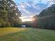 Expansive backyard with mature trees and a shed at dusk at 2900 Orchard Sw Rd, Conyers, GA 30094