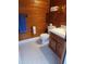Rustic bathroom with wood paneled walls, white tiled floor, and a simple sink and toilet at 2900 Orchard Sw Rd, Conyers, GA 30094