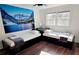 Comfortable bedroom featuring two twin beds, wood floors, natural light from the window, and mountain themed wall art at 2900 Orchard Sw Rd, Conyers, GA 30094