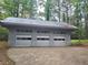 Large three car garage with concrete parking and metal roof sits among the trees at 2900 Orchard Sw Rd, Conyers, GA 30094