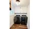 Clean laundry room featuring modern, black, front-load washer and dryer, with white cabinets, and wood-look flooring at 2900 Orchard Sw Rd, Conyers, GA 30094