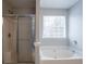The bathroom features a window, tub, and shower with glass doors at 3870 Golfe Links Dr, Snellville, GA 30039