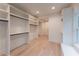 Spacious walk-in closet with custom shelving, a window seat, and hardwood flooring at 4955 Chamblee Dunwoody Rd, Dunwoody, GA 30338