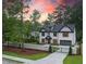 Gated driveway leading to a two-story brick home with manicured lawn and colorful sunset at 4955 Chamblee Dunwoody Rd, Dunwoody, GA 30338