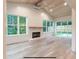Living room showcasing a brick fireplace, hardwood floors, and large windows with views of lush greenery at 4955 Chamblee Dunwoody Rd, Dunwoody, GA 30338