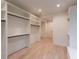 Custom walk-in closet with abundant shelving and drawers for clothing and accessories, plus wood flooring at 4955 Chamblee Dunwoody Rd, Dunwoody, GA 30338