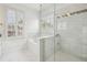 Bright bathroom featuring a glass-enclosed shower with white marble tiles and a separate tub beneath a window at 565 Rose Garden Ln, Alpharetta, GA 30009