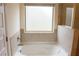 Bright bathroom with white garden tub with a frosted window to allow natural light at 150 Canal St, Hampton, GA 30228