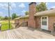 View of the spacious wooden deck and brick exterior featuring a brick chimney and white door at 7928 S Giles Rd, Douglasville, GA 30135