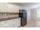 Functional kitchen with tiled floors, black appliances, granite countertops, and white cabinets at 7928 S Giles Rd, Douglasville, GA 30135