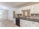 This kitchen features white cabinets, granite countertops and sink, with wood-look tile flooring at 7928 S Giles Rd, Douglasville, GA 30135