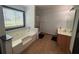 Bathroom boasting a soaking tub with tiled walls and a single sink vanity with neutral flooring at 1087 Yellow River Dr, Lawrenceville, GA 30043