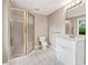 Bathroom features a shower with glass doors, a white vanity, and neutral tile flooring with a bright window view at 515 Old Chartwell Xing, Alpharetta, GA 30022