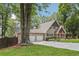 View of a home's exterior, showing the garage, front yard, and mature trees around the property at 890 Lake Dr, Snellville, GA 30039