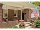 Inviting front porch features a swing and brick columns, complemented by vibrant flowers and a charming American flag at 1371 N Highland Ne Ave, Atlanta, GA 30306