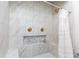Shower featuring marble tile, gold fixtures, a built-in bench, and a small decor accent niche at 1443 Fama Ne Dr, Atlanta, GA 30329