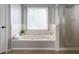 Bright bathroom featuring a soaking tub, tile floors, and a glass shower at 303 Roswell Green Ln, Roswell, GA 30075