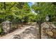 Close-up of a gated driveway with decorative stone pillars and lush greenery at 11270 Stroup Road, Roswell, GA 30075