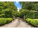 Private driveway entrance with lush greenery, stone pillars, and mature trees at 11270 Stroup Road, Roswell, GA 30075