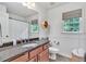 Bathroom with wood vanity, granite countertop, framed mirror, tiled floor, toilet and window at 1637 Willow Way, Woodstock, GA 30188