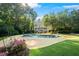 Lush backyard oasis featuring a large in-ground pool, mature trees, and landscaped garden at 2390 Sassafrass Ln, Powder Springs, GA 30127
