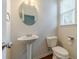 Cozy half bathroom featuring a pedestal sink, toilet, round mirror, and natural lighting from a window at 3255 Clear View Dr, Snellville, GA 30078