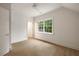 Sunlit bedroom with light hardwood floors, white trim, a ceiling fan, and a window overlooking lush greenery at 3916 E Brookhaven Ne Dr, Brookhaven, GA 30319