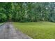 Exterior view of home with a long driveway, grassy front yard, and wooded surroundings at 911 White Stag Ln, Canton, GA 30115