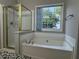 A luxurious bathtub with tiled backsplash under a window with natural light and a gold-framed shower at 1415 Stoney Field Pl, Lawrenceville, GA 30043