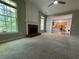 Spacious living room featuring plush carpet flooring, a classic fireplace, and open view to the kitchen at 1415 Stoney Field Pl, Lawrenceville, GA 30043