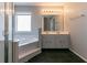 Bright bathroom featuring a soaking tub and double vanity with a large mirror and modern lighting at 12015 Harbour Town Pkwy, Fayetteville, GA 30215