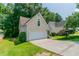 Side view of a tan home showcasing a two-car garage and driveway at 12015 Harbour Town Pkwy, Fayetteville, GA 30215