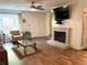 Cozy living room featuring a brick fireplace, hardwood floors, a ceiling fan, and ample natural light at 210 Mill Creek Pl, Roswell, GA 30076